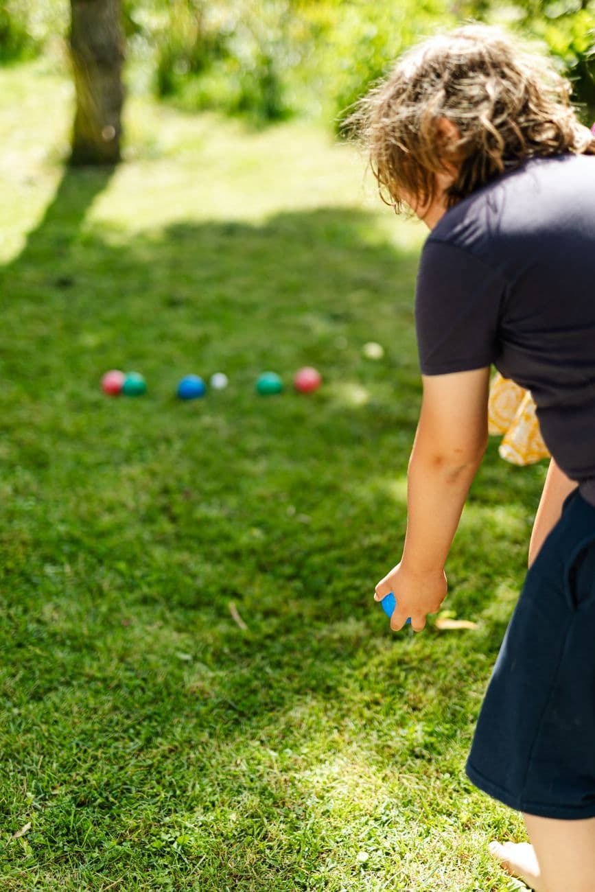 A child playing a ball game on green grass outdoors during a sunny day.