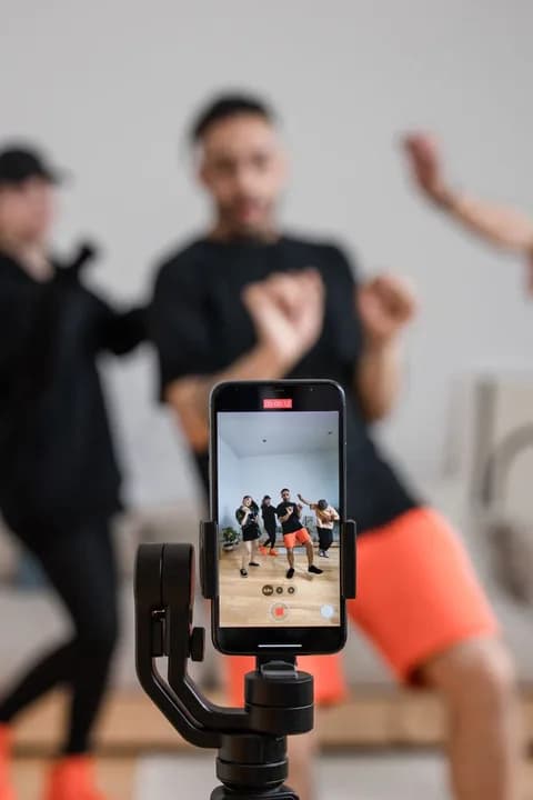 A group of people recording a dance video using a smartphone indoors. PNG