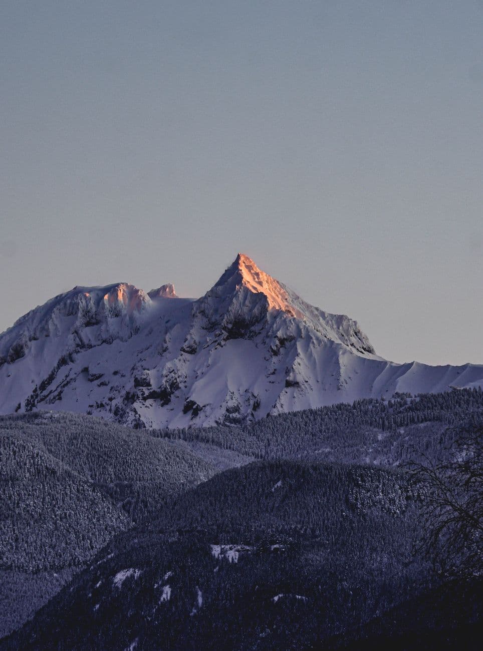 Captivating view of snow-covered mountain peak at sunrise with clear sky.