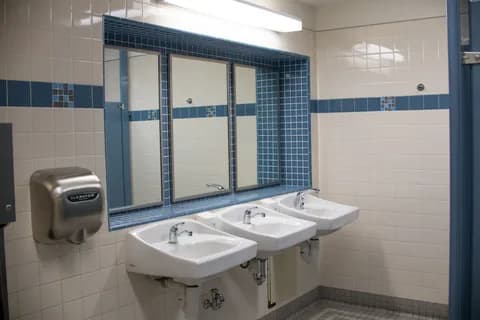 Clean and bright public bathroom with sinks, mirrors, and a hand dryer. PNG