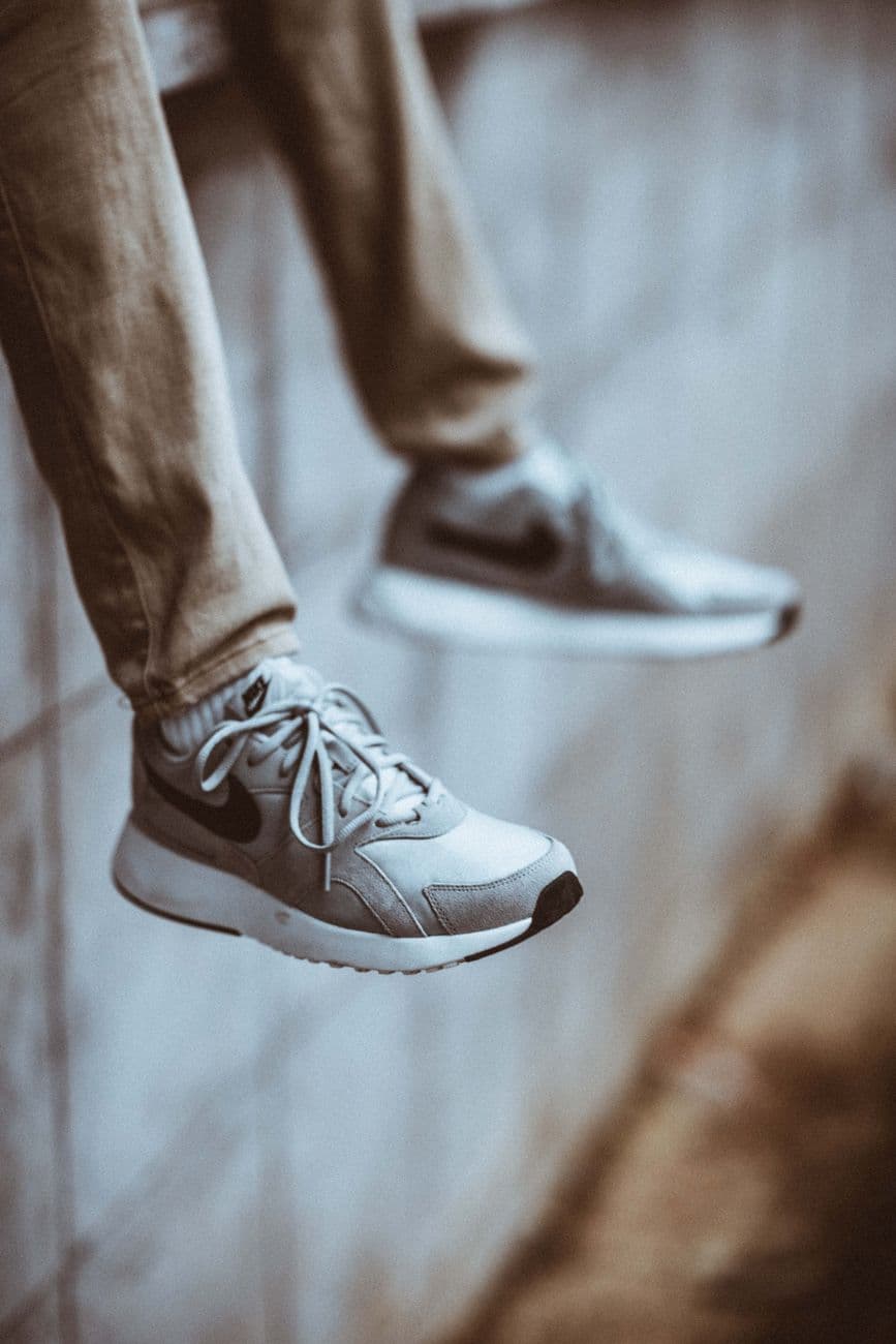 Close-up of stylish sneakers and denim pants on a casual hanging pose.