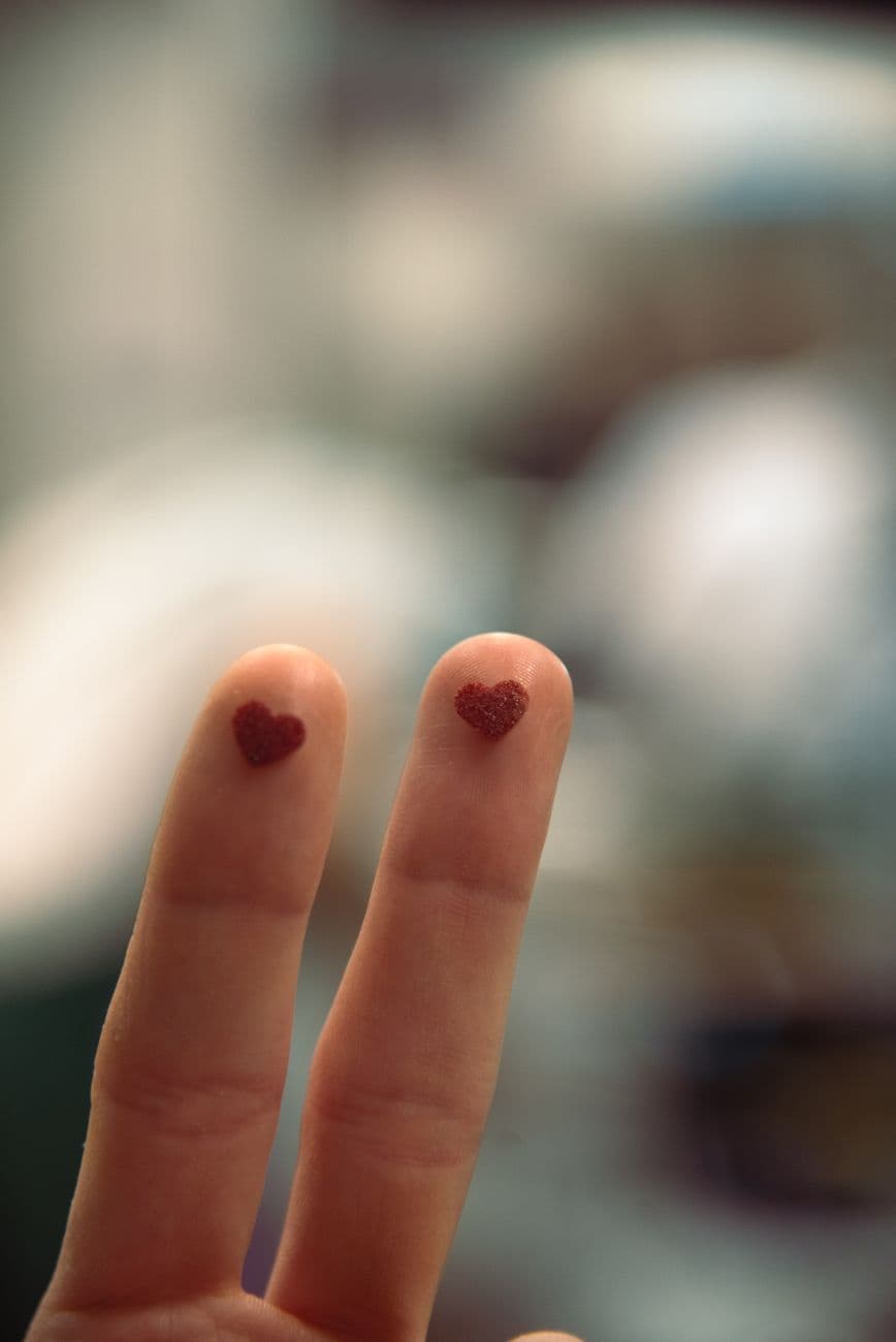Close-up of two fingers with heart symbols, representing love and affection.