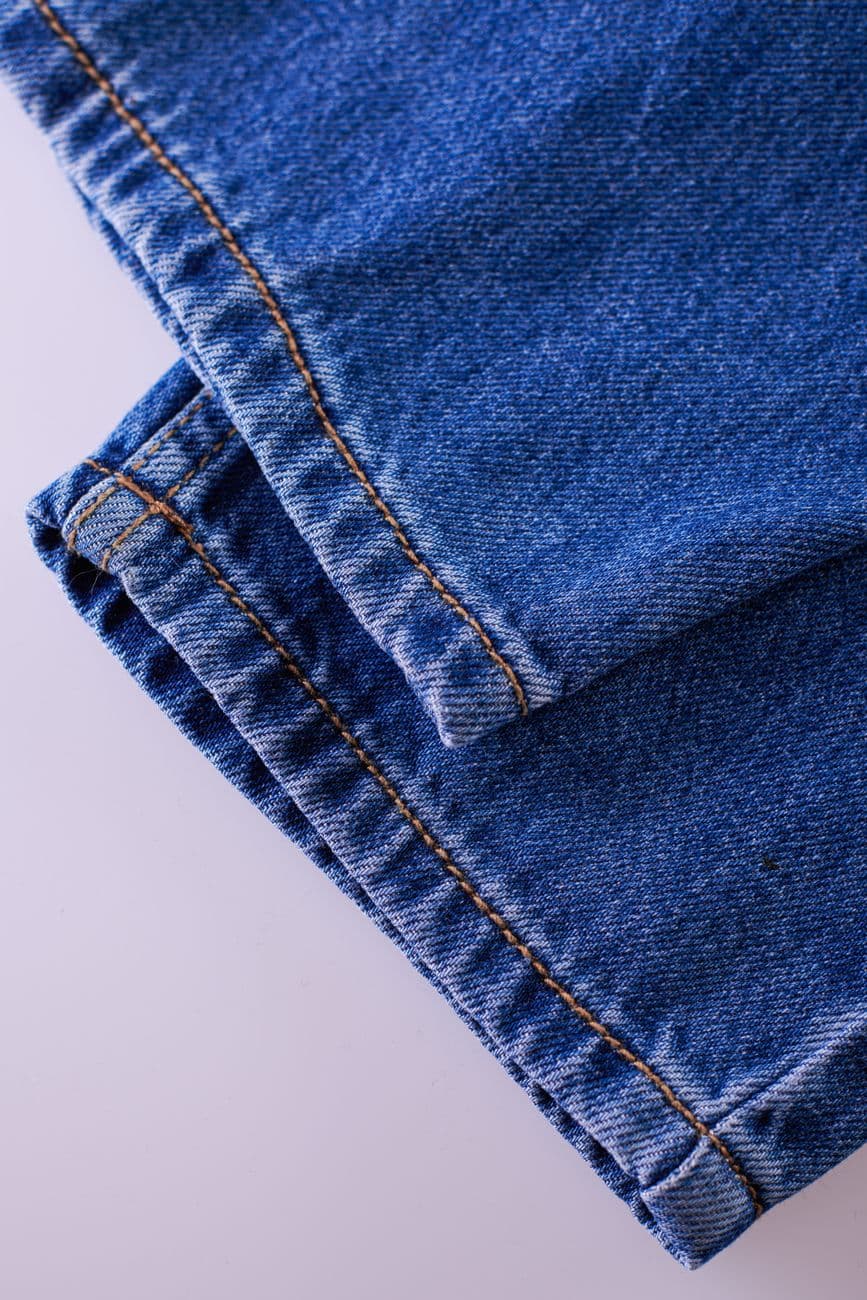 Detailed view of blue denim jeans focusing on stitching and texture.