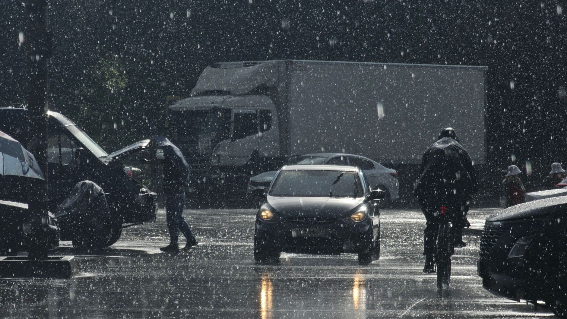 Moody urban street scene in heavy rain with cars and pedestrians.