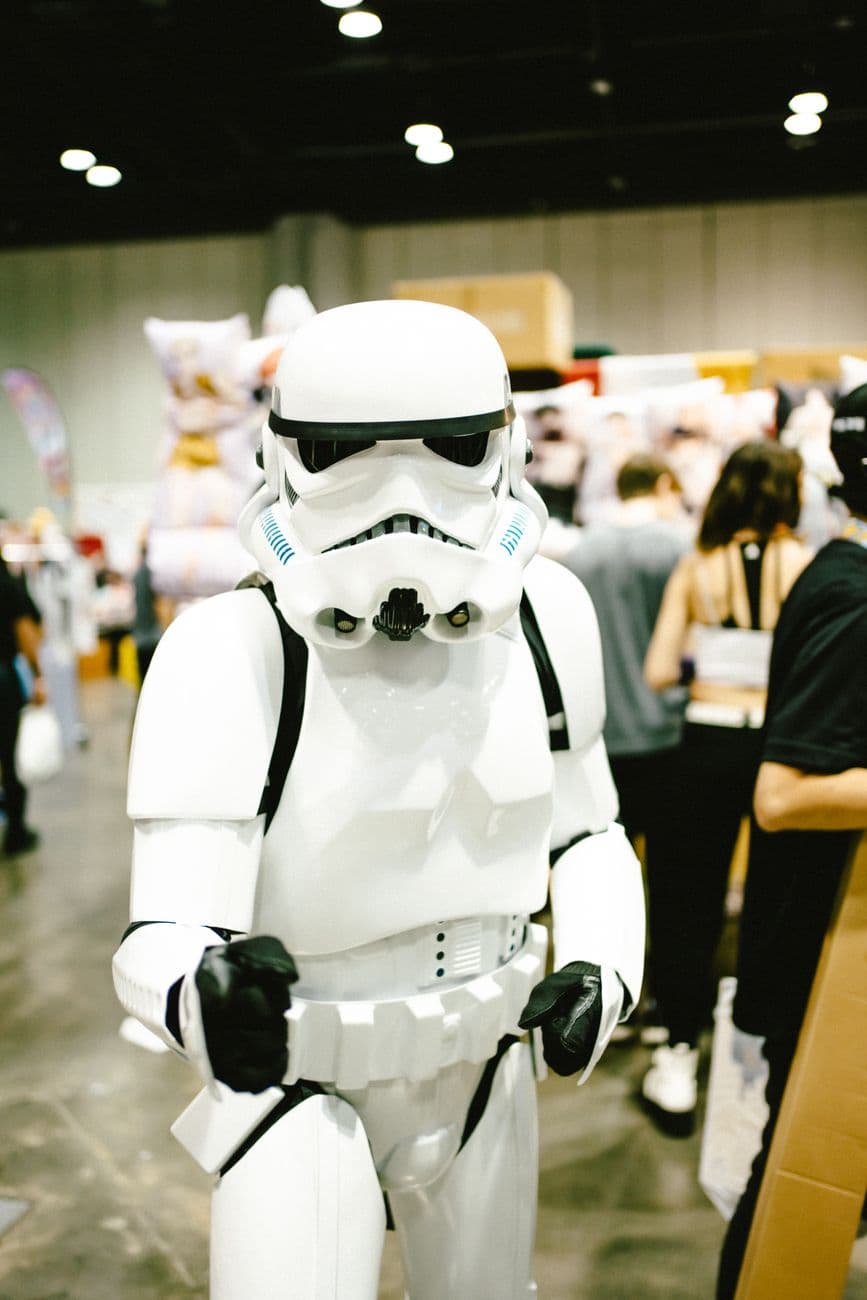 Person in stormtrooper costume at a lively pop culture event indoors.