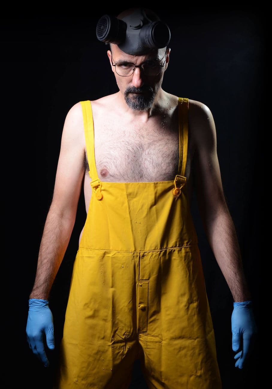 Portrait of a man wearing yellow overalls and a gas mask, signifying safety.