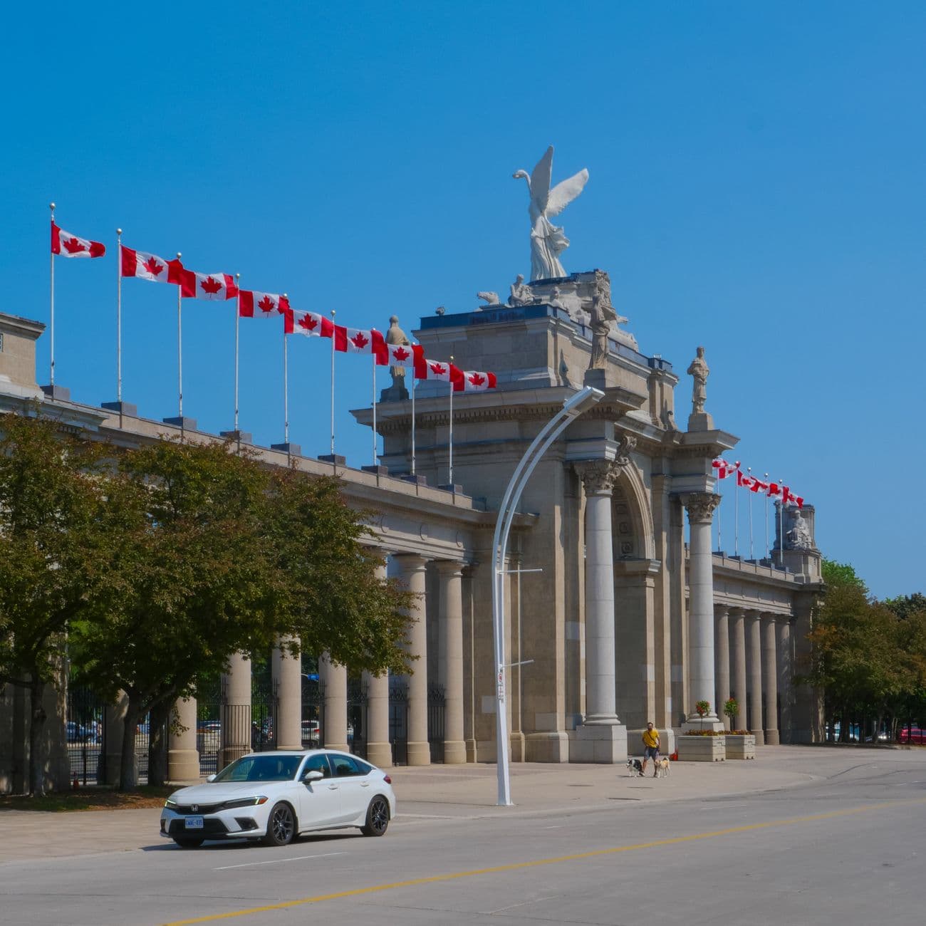 Toronto's iconic Princes' Gates adorned with Canadian flags on a sunny day.