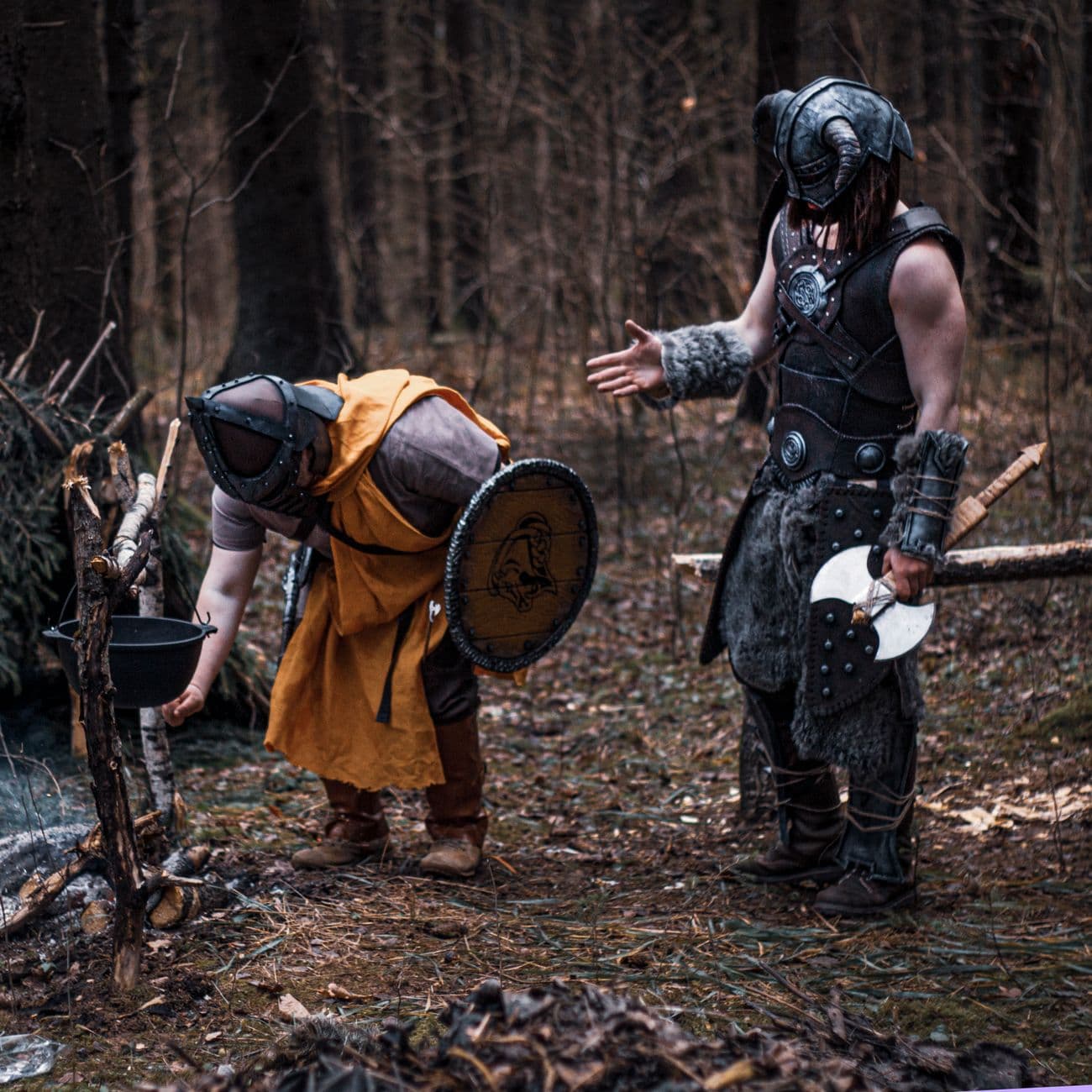 Two Viking warriors in armor interact in a forest, evoking medieval times.