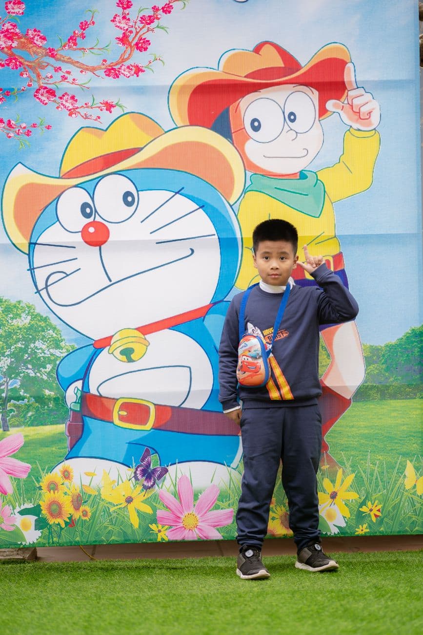 Young boy posing in front of a vibrant cartoon mural outdoors.
