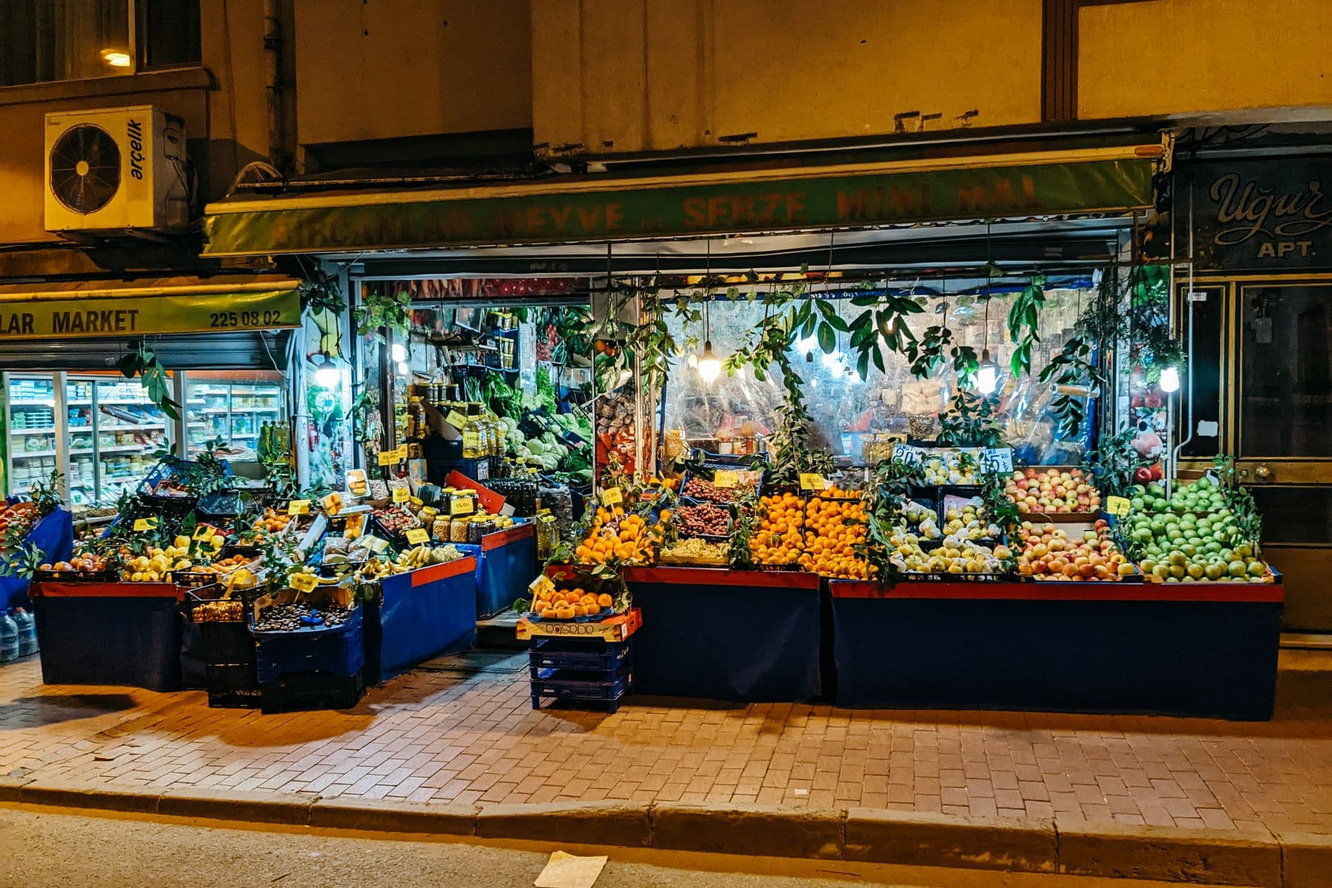 A bustling night market stall offering a colorful array of fresh fruits and vegetables on