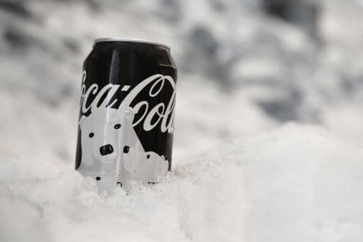 A close-up of a Coca-Cola can covered in frost and surrounded by snow, evoking a wintery a PNG