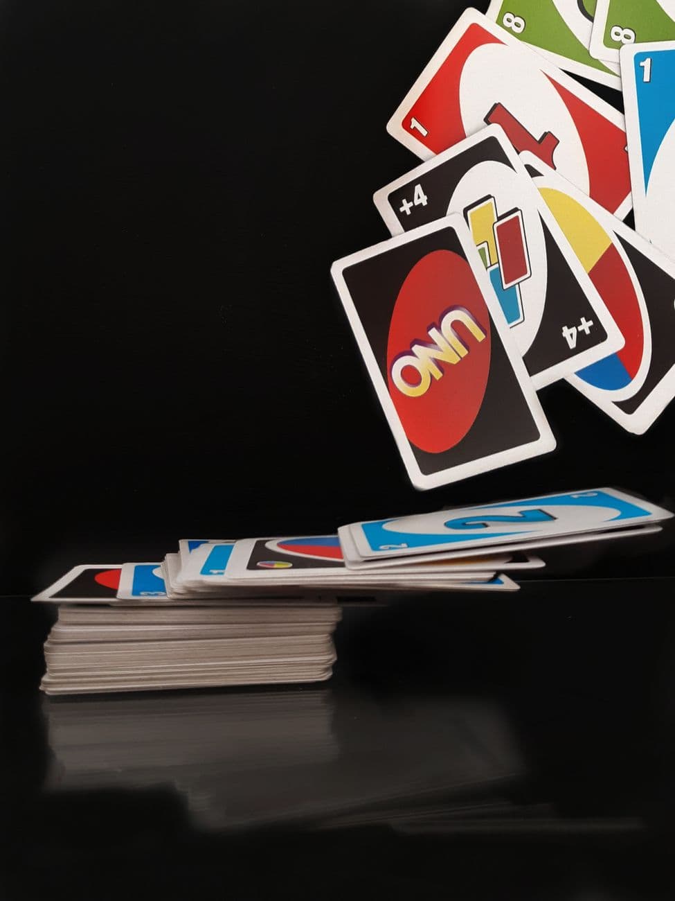 A dramatic view of UNO cards flying mid-air on a black background, capturing the essence o