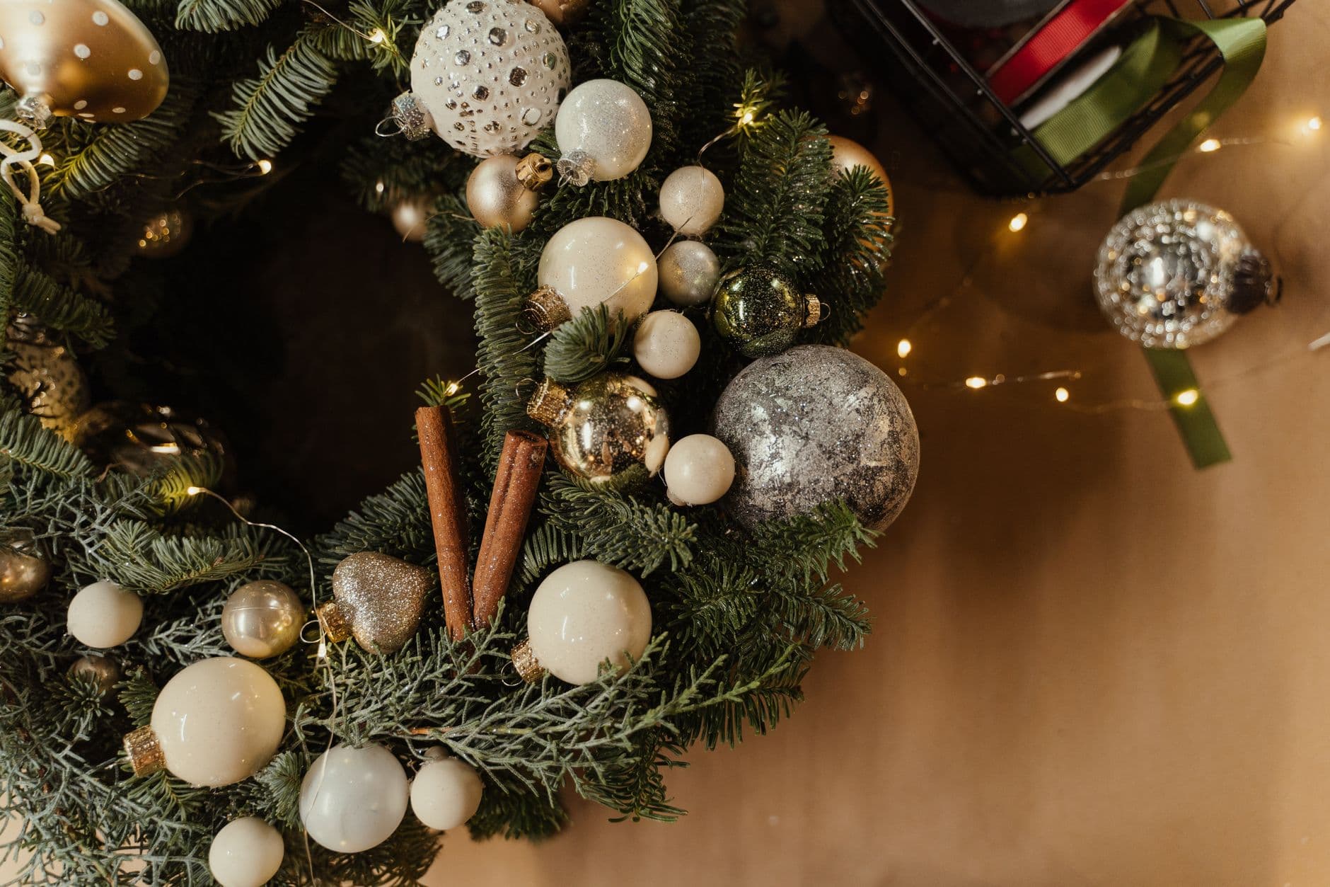 A festive Christmas wreath adorned with baubles, cinnamon sticks, and twinkling lights, pe