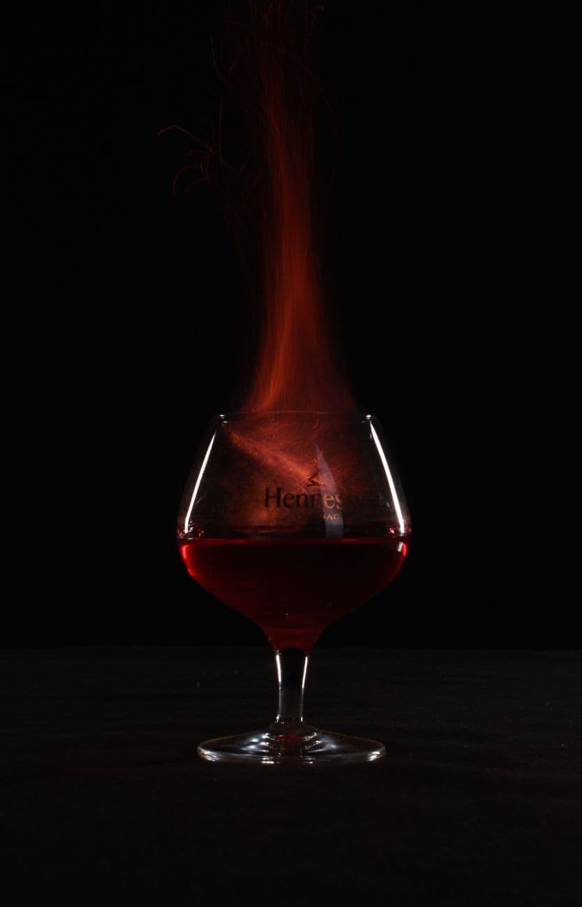 A glass of cognac with a captivating fire effect against a dark background, creating a dra