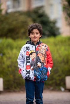 A happy child smiling while wearing a colorful Roblox hoodie, posing outdoors in a natural PNG