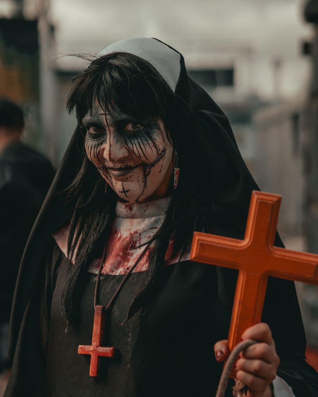 A haunting Halloween portrait of a woman dressed as a nun holding a cross with eerie makeu