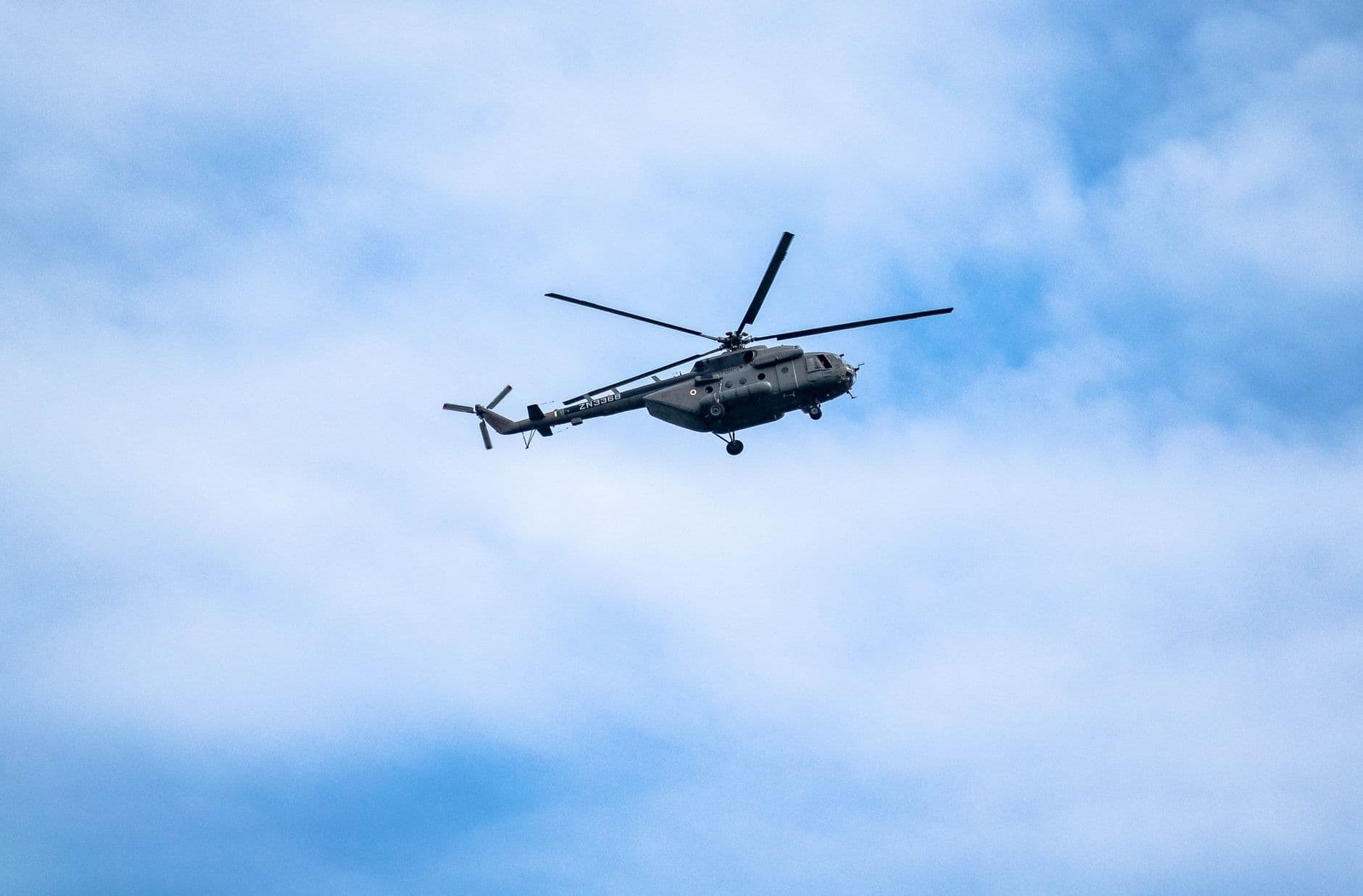 A military helicopter flying in a clear blue sky, showcasing aerial dynamics and engineeri