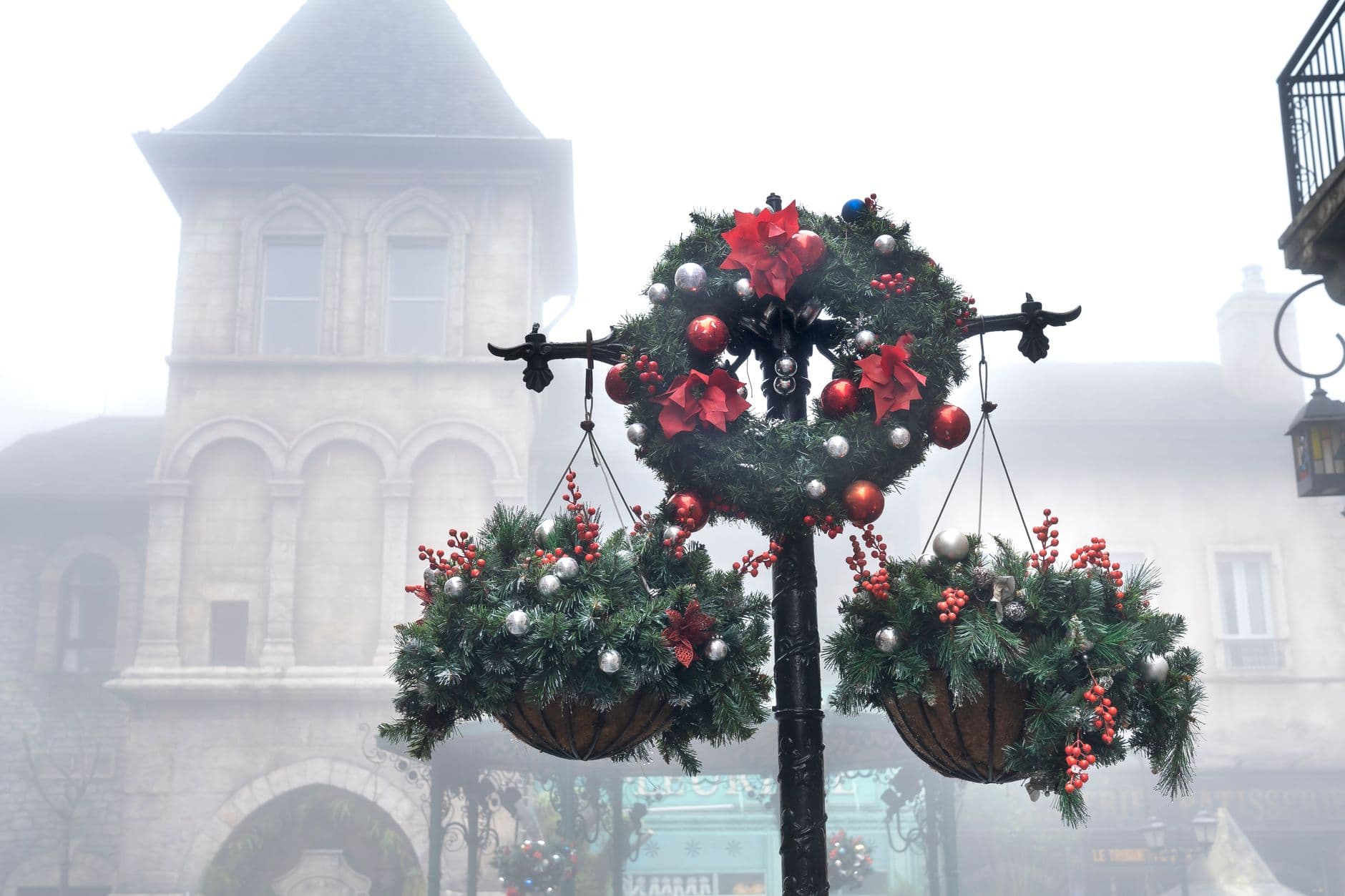 A misty town street adorned with festive Christmas wreaths and baubles, creating a cozy wi