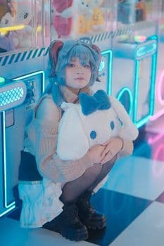 A person cosplays with blue wig and stuffed toy in a colorful arcade setting. PNG