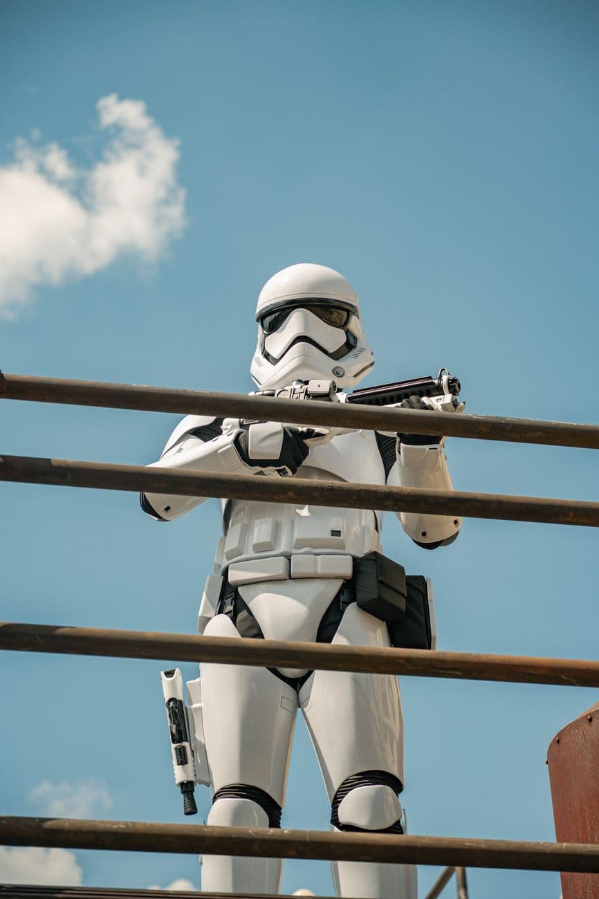 A person in stormtrooper costume stands on an outdoor platform with a blue sky background.