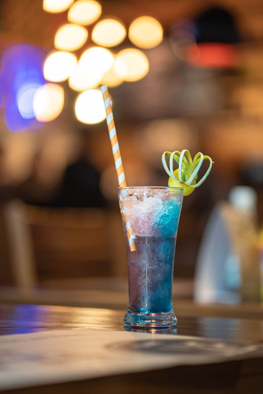 A refreshing cocktail with vibrant colors and citrus garnish in a lively bar setting.