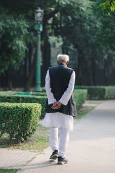 A senior adult man strolling through a peaceful park, enjoying nature's tranquility. PNG