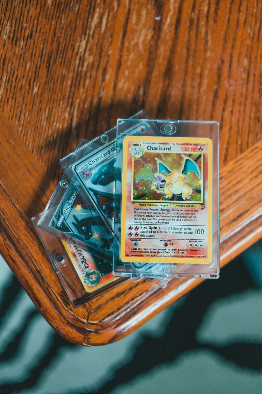 A set of valuable Pokemon trading cards displayed in protective cases on a wooden table.