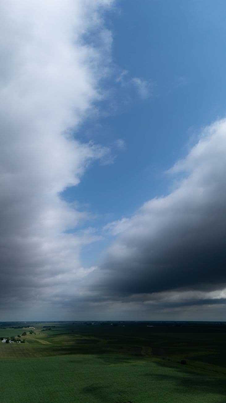 A vast cloudy sky with green farmland below, depicting dramatic weather conditions.