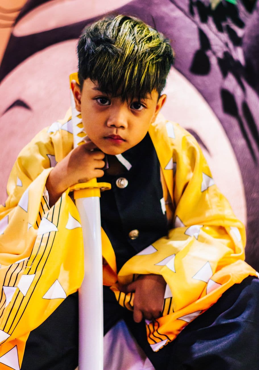A young child in a colorful costume, holding a sword with a serious expression.