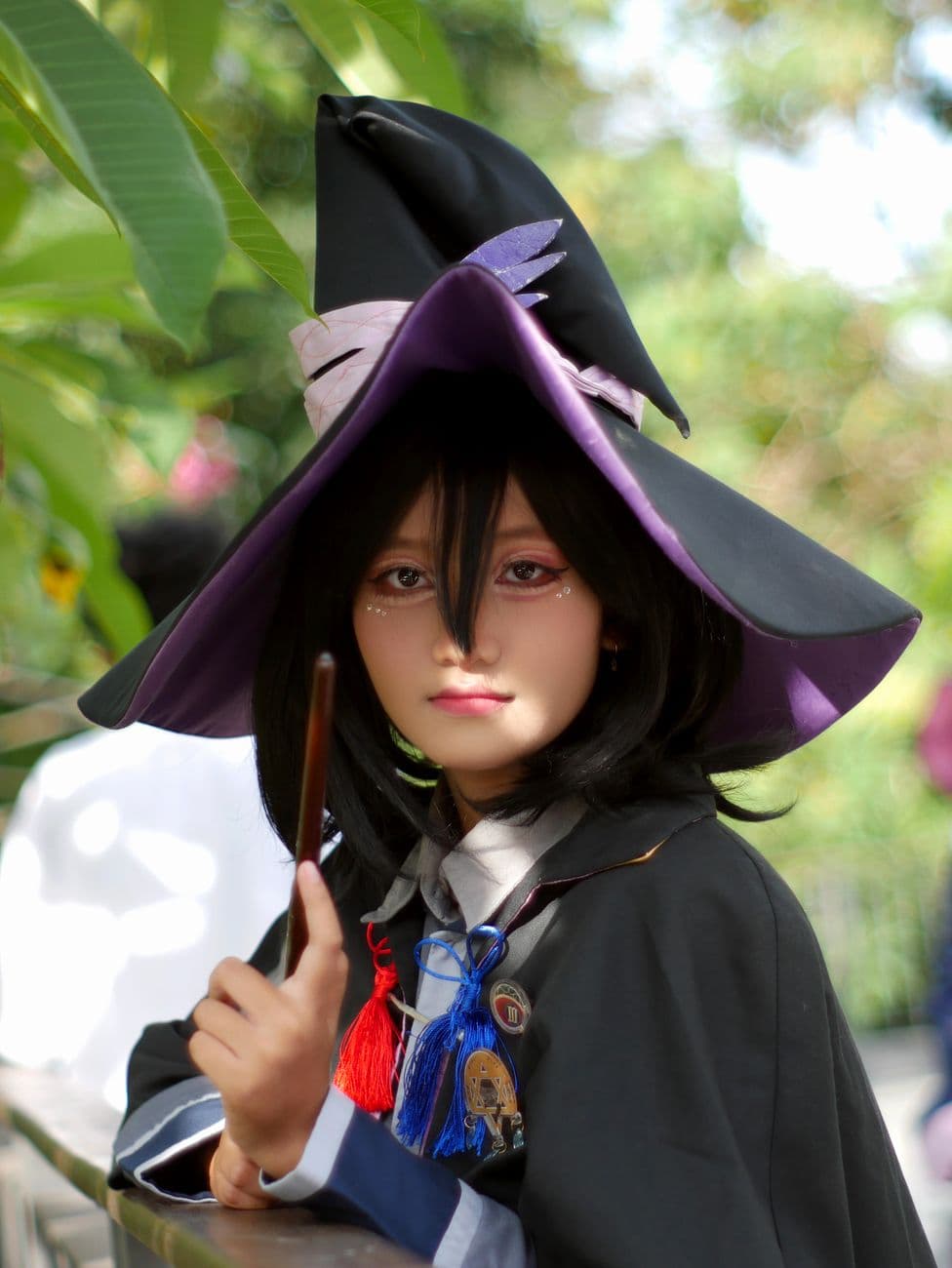 A young cosplayer in an enchanting witch costume with a purple hat and magic wand, capture
