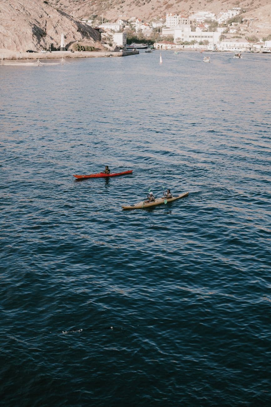 Aerial view of kayakers enjoying leisure activities on a calm sea with a coastal backdrop.
