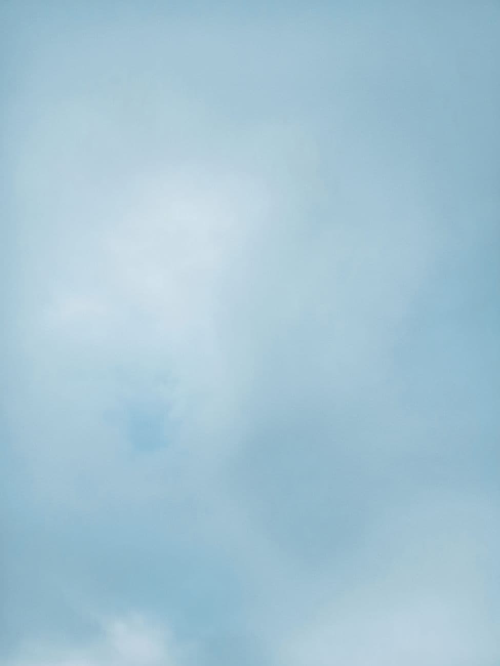 An expansive view of a clear blue sky with gentle wispy clouds creating a peaceful atmosph