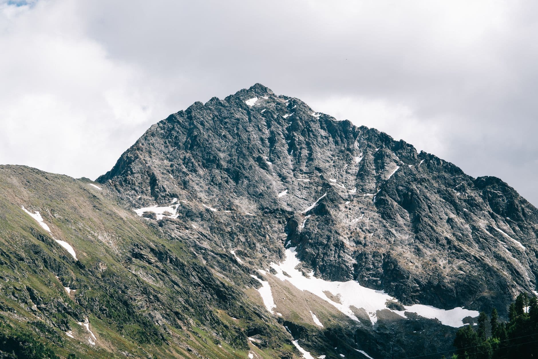Breathtaking view of a snow-capped mountain peak under a cloudy sky, showcasing natural be