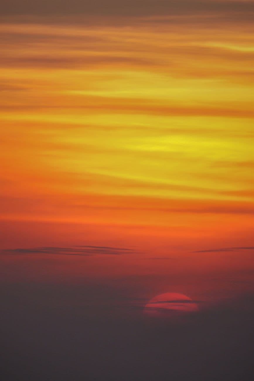 Capture of a vibrant sunset sky with bold reds, oranges, and yellows creating a dramatic a
