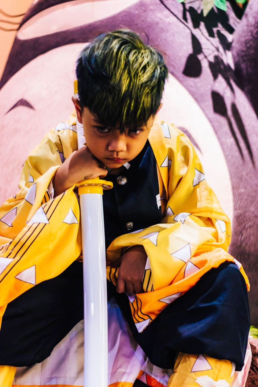 Child dressed in anime-style costume with a contemplative expression. Vibrant and artistic
