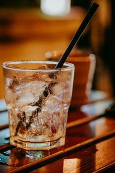 Close-up of a chilled drink with ice cubes and straw on a wooden surface, perfect for summ PNG