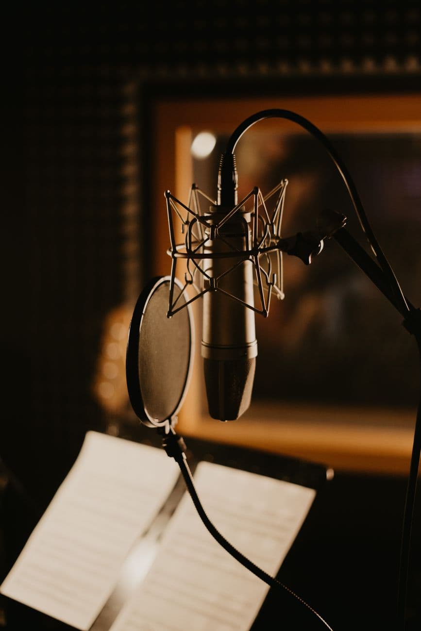 Close-up of a microphone and pop filter in a dimly lit recording studio, perfect for music