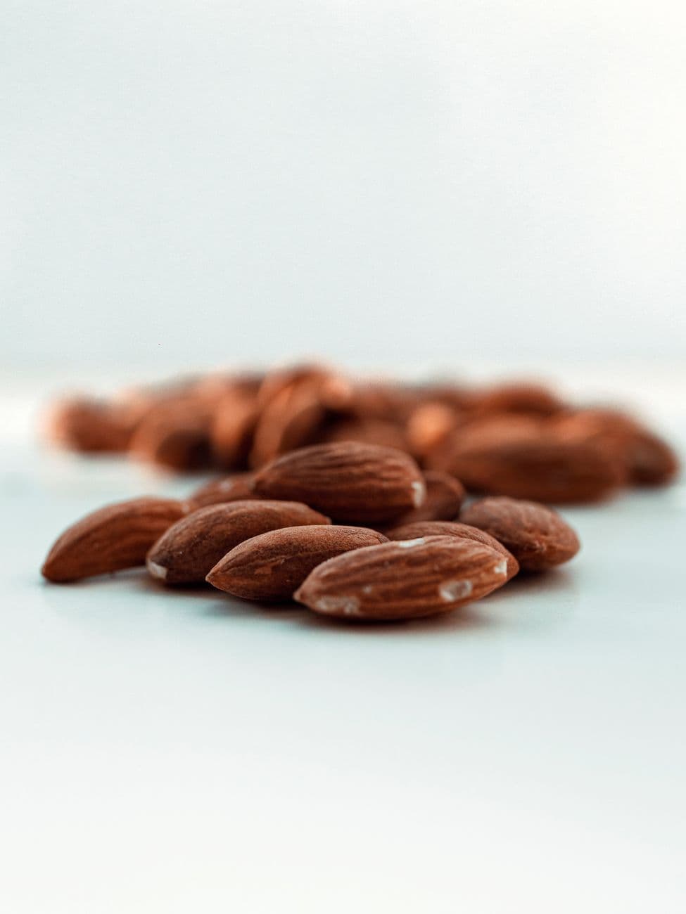 Close-up of fresh almonds on white background, highlighting texture and color.