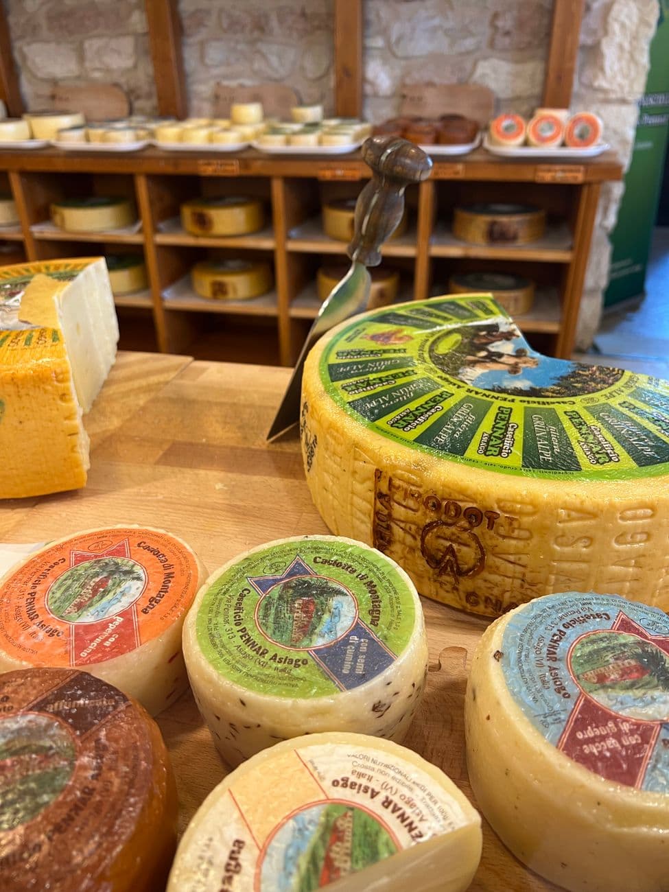 Close-up view of a selection of artisan cheeses with wooden knife in cozy cheese shop.