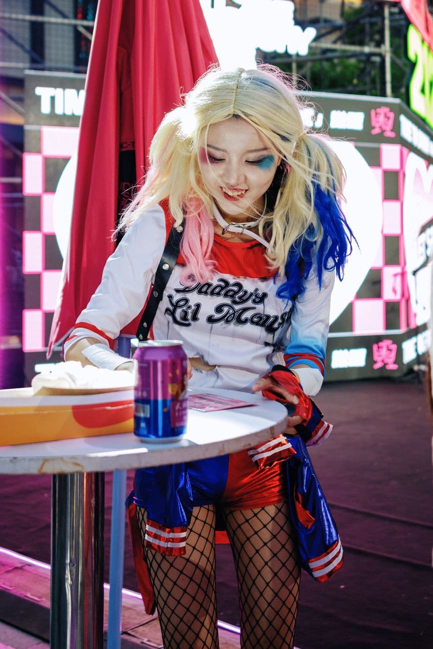 Colorful Harley Quinn cosplayer at an outdoor festival, engaging in fun activities.
