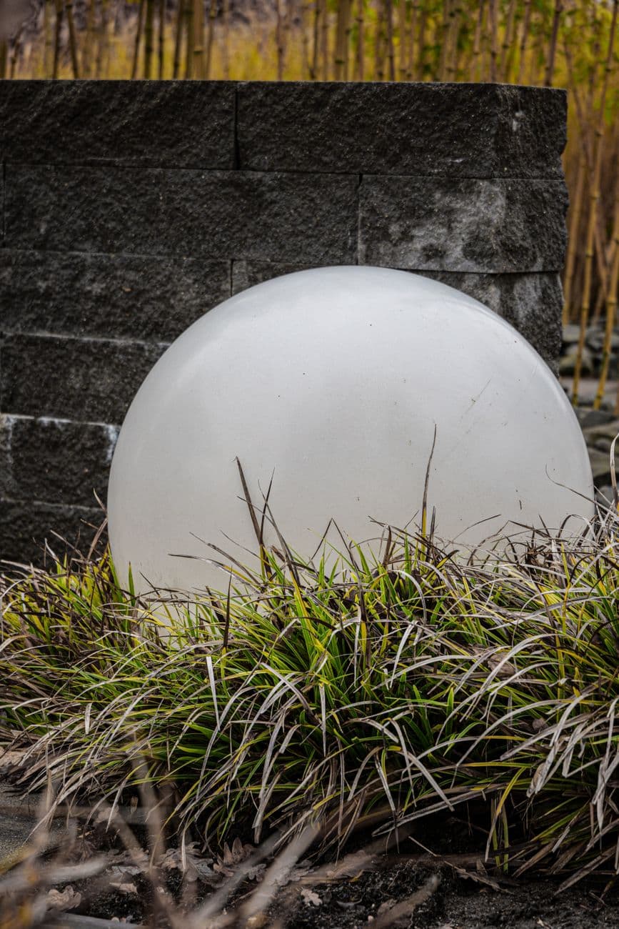 Contemporary outdoor decoration with a large white sphere and ornamental grasses in a land
