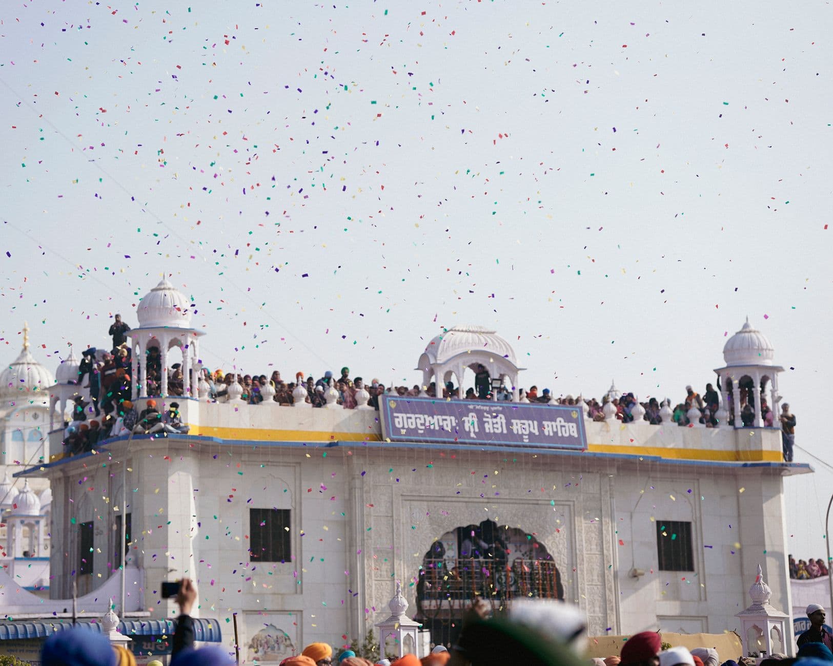 Crowds gather at a classic dome for a traditional festival with colorful confetti in the a