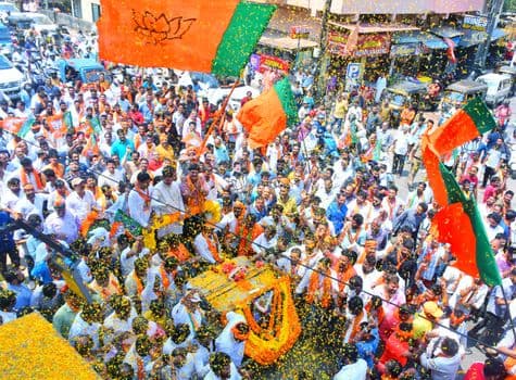 Crowds gather in Mangaluru for a colorful street parade with vibrant flags and decorations PNG