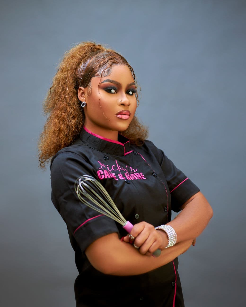 Culinary professional in black chef's attire holding a whisk, showcasing confidence and ex
