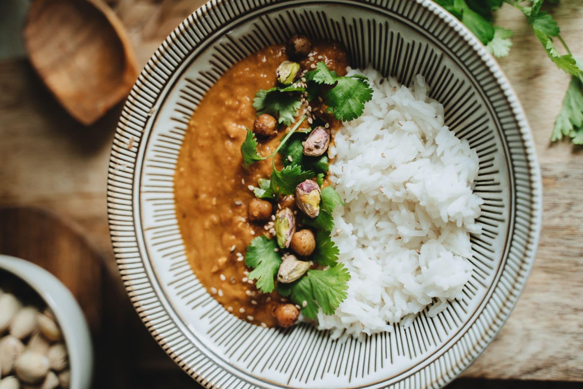 Delicious vegan rice bowl featuring lentil curry, topped with pistachios, cilantro, and se