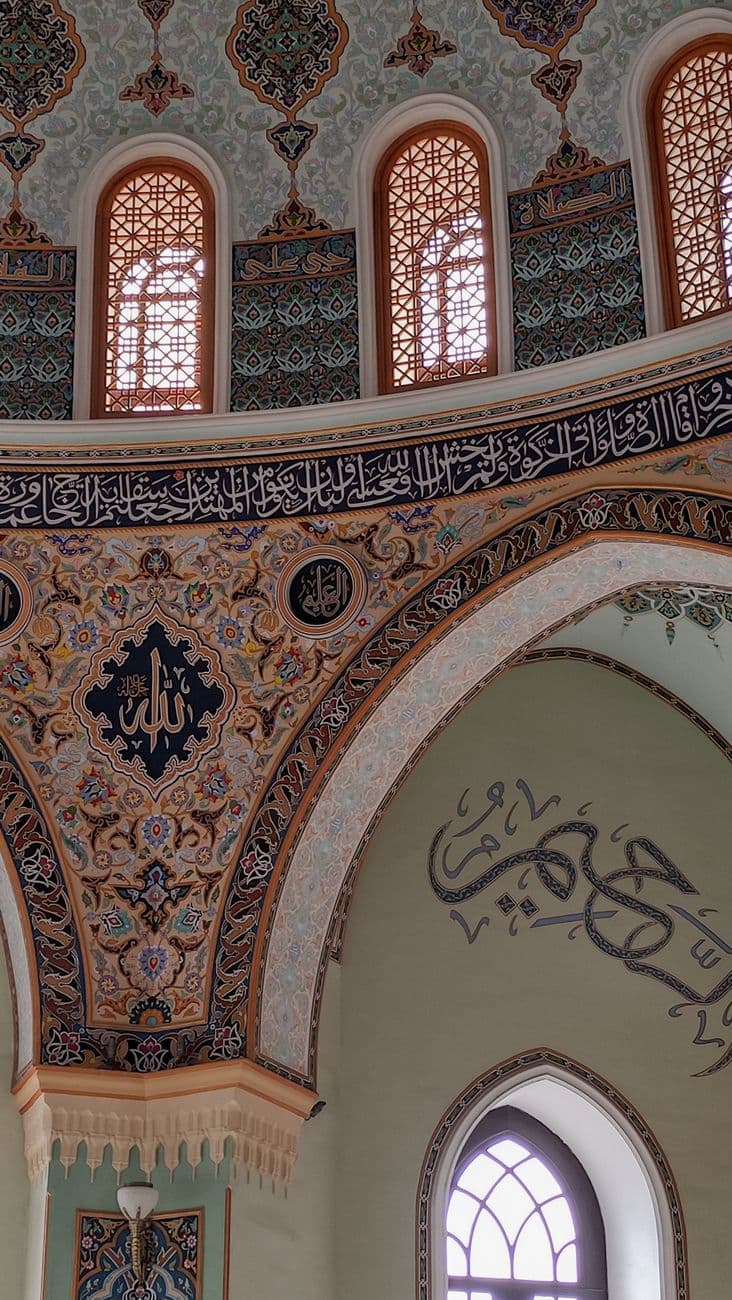 Detailed view of intricate Islamic mosaic artwork in a mosque interior featuring Arabic ca