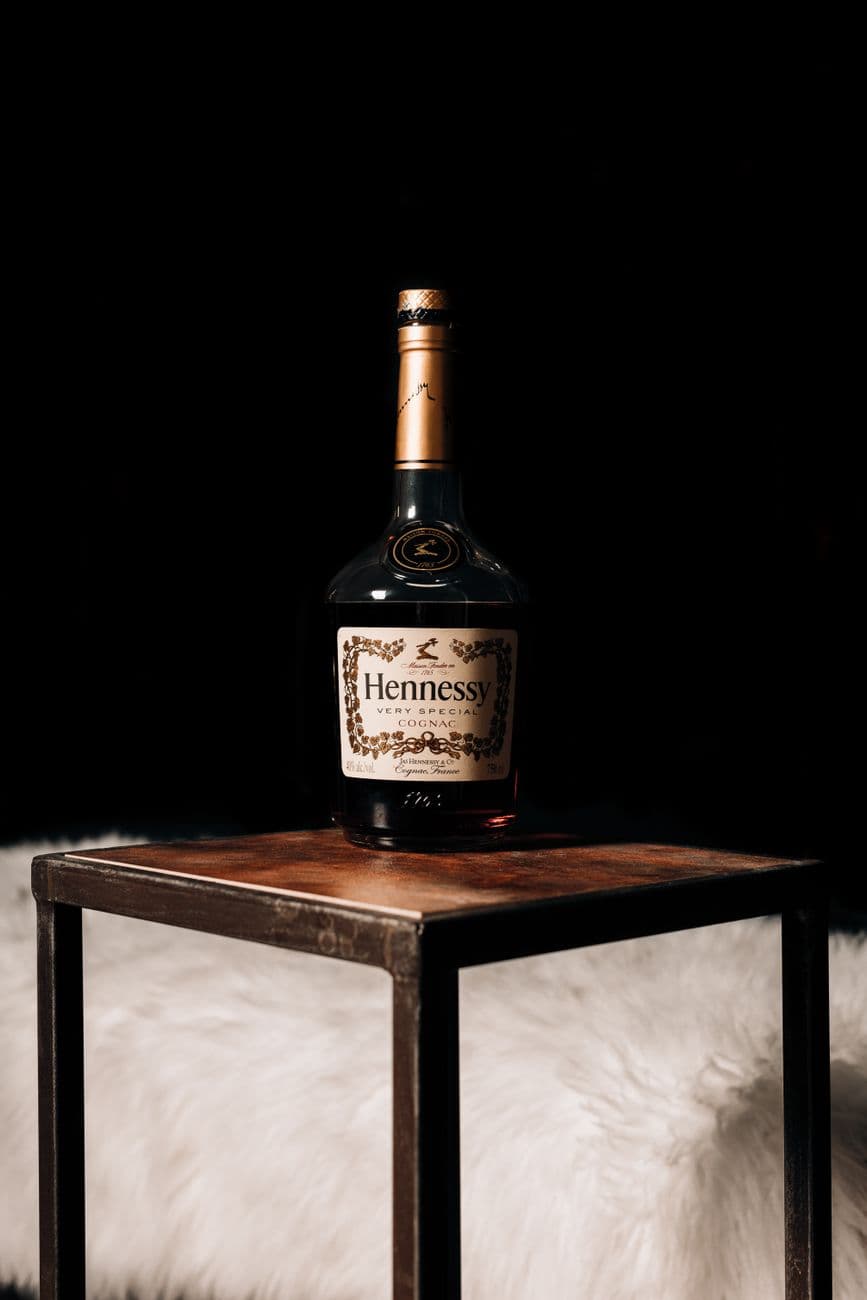 Elegant Hennessy bottle placed on a sleek table against a dark backdrop. Perfect for luxur
