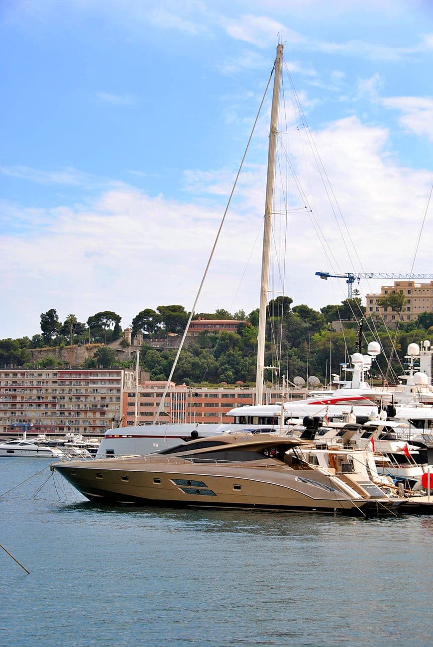 Elegant yachts docked at a marina in Monaco under clear blue skies. Perfect summer getaway