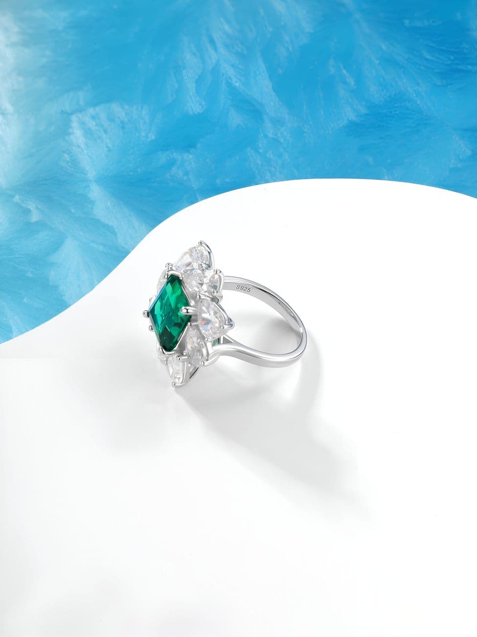 Emerald-cut ring with diamond cluster, showcasing luxury and elegance.