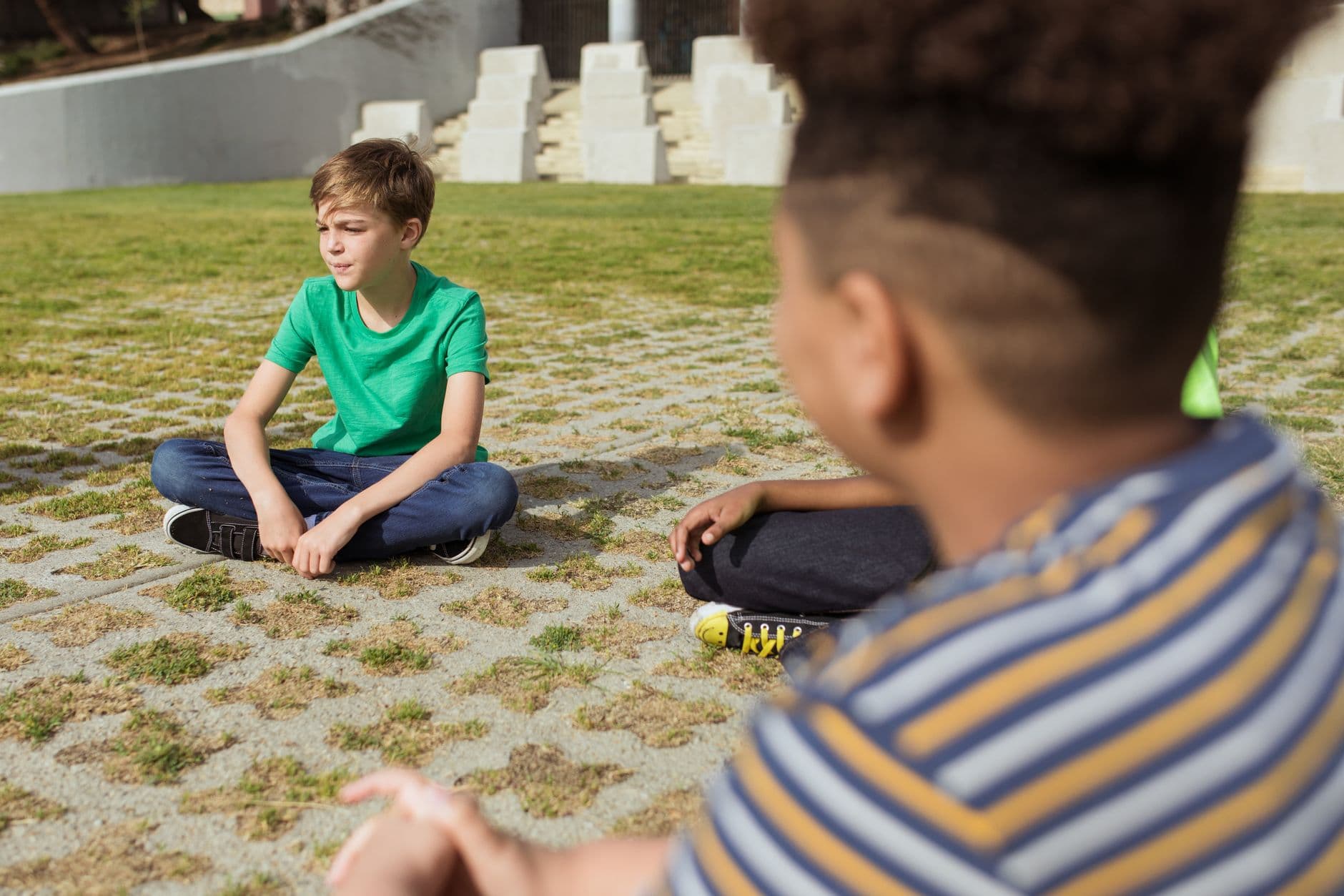 Group of children sitting in a park with bright sunlight, creating a peaceful atmosphere.